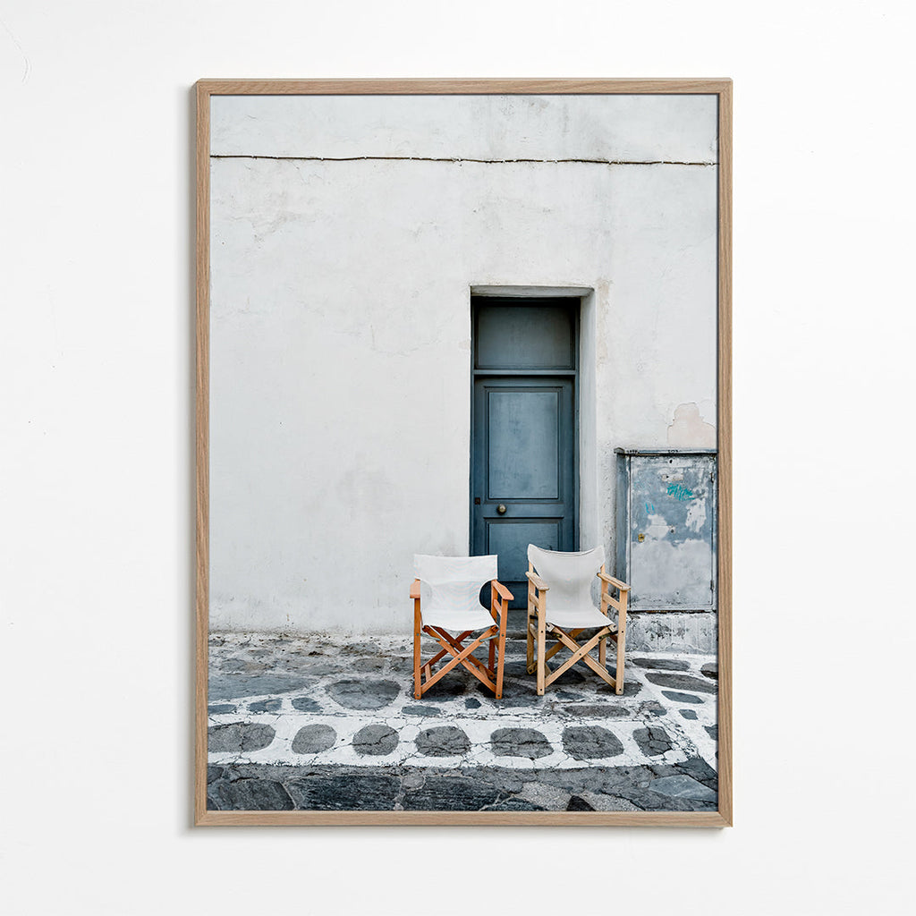 Fotografie modrých dveří s dvěma židlemi